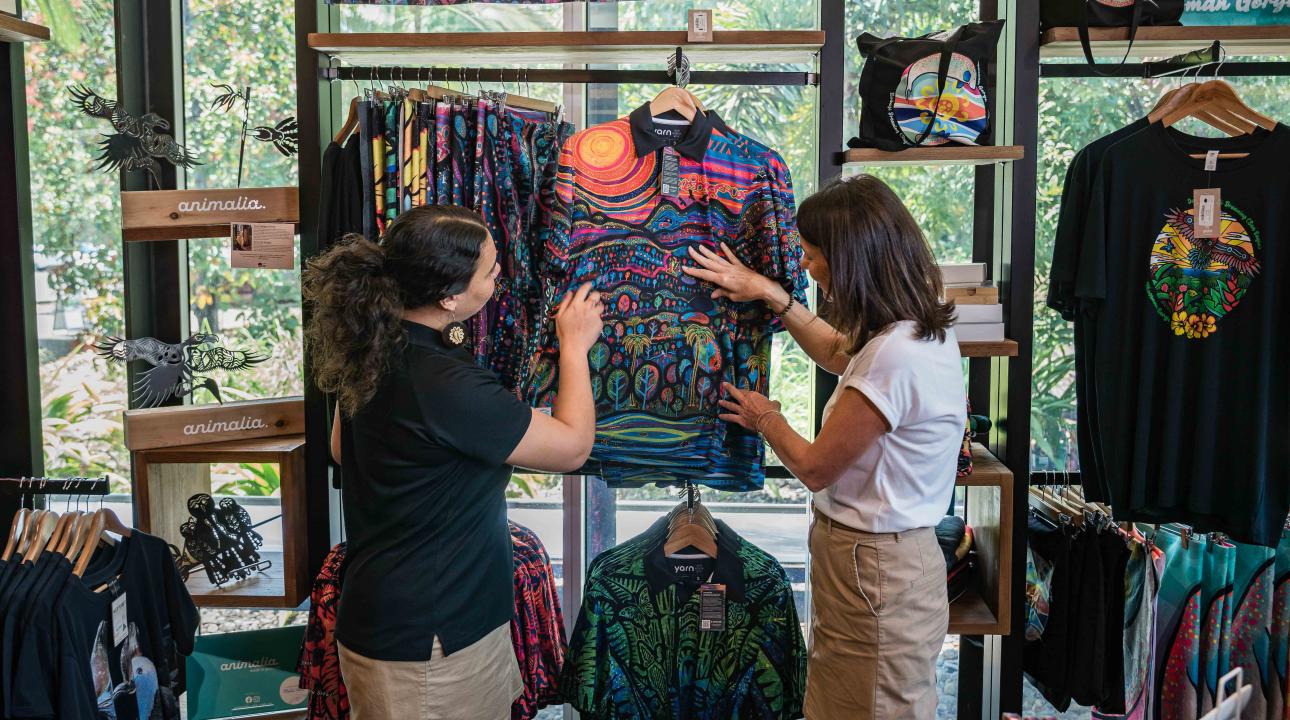 Retail Staff member helping a visitor select a shirt from the Gift Shop at Mossman Gorge Cultural Centre